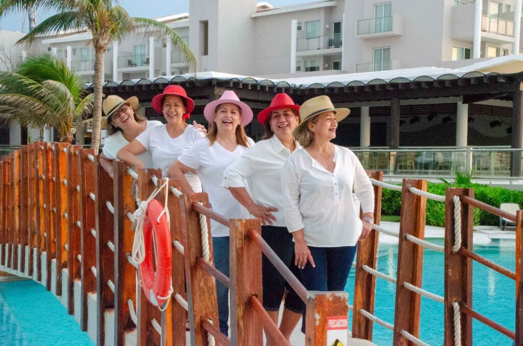 Five ladies wearing huts with a nice swimming pool hotel background