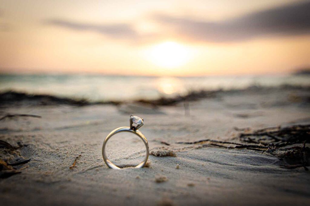 Beautiful engagement ring placed on the white sand of Cancun